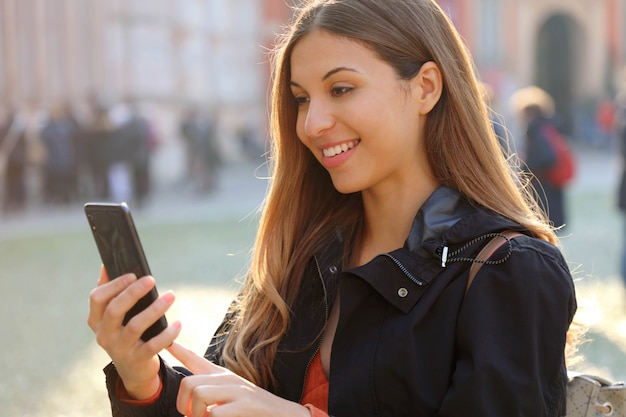 Glimlachende vrouw die haar smartphone gebruikt