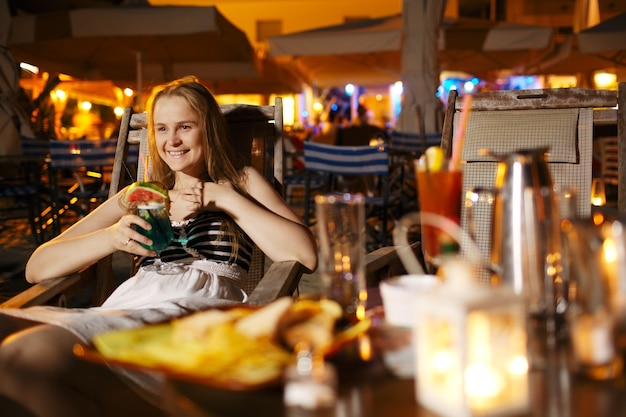 Glimlachende vrouw die in een cafetaria drinkt