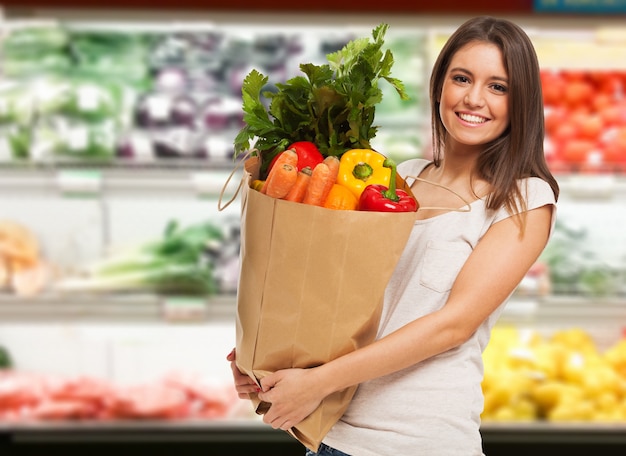 Glimlachende vrouw die in een supermarkt winkelt