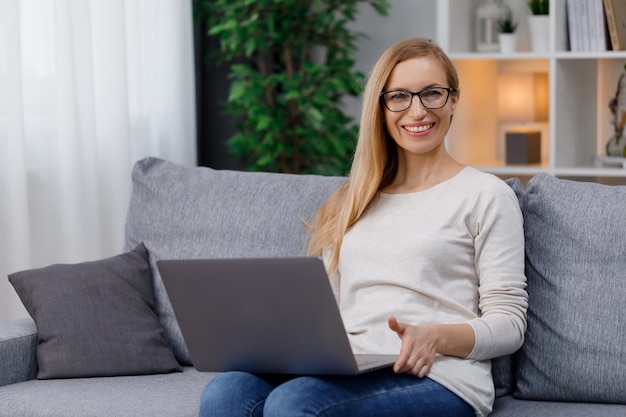 Glimlachende vrouw die laptop met behulp van