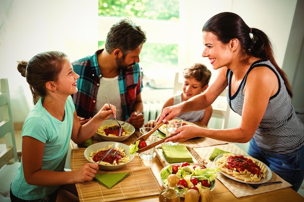 Glimlachende vrouw die maaltijd aan familie serveert