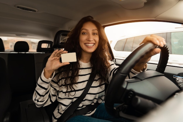 Glimlachende vrouw die nieuwe auto bestuurt met rijbewijs