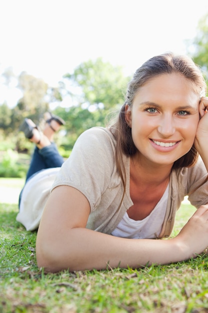 Glimlachende vrouw die op het gras legt