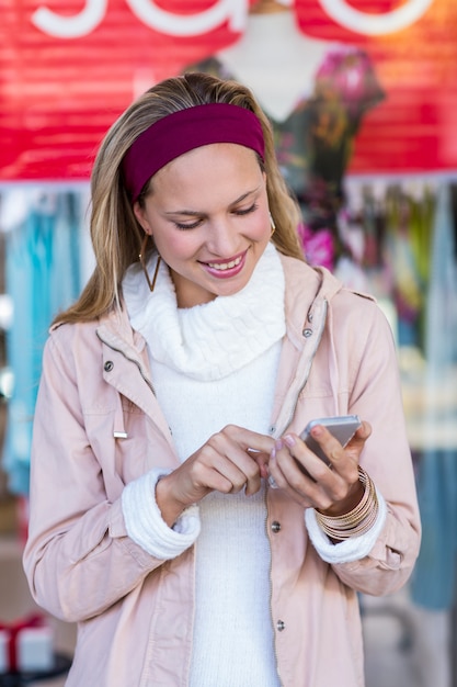 Glimlachende vrouw die smartphone voor venster gebruiken