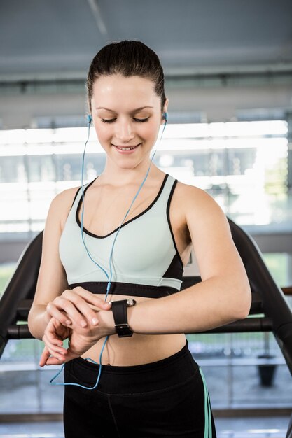 Glimlachende vrouw die smartwatch in de gymnastiek bekijkt