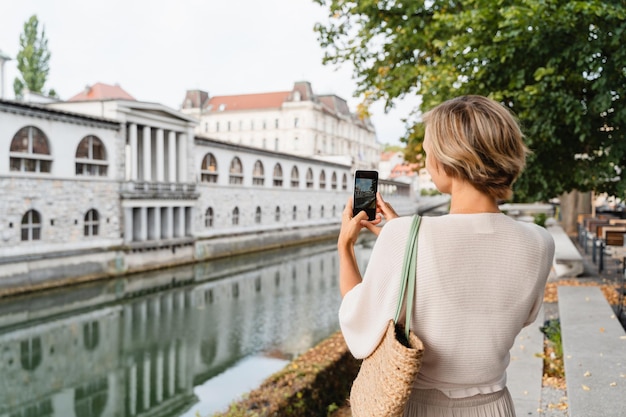 Glimlachende vrouw die stadsarchitectuur van de oude stad van Ljubljana fotografeert Slovenië Reizen Europa