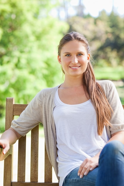 Glimlachende vrouw die van haar dag op een parkbank geniet