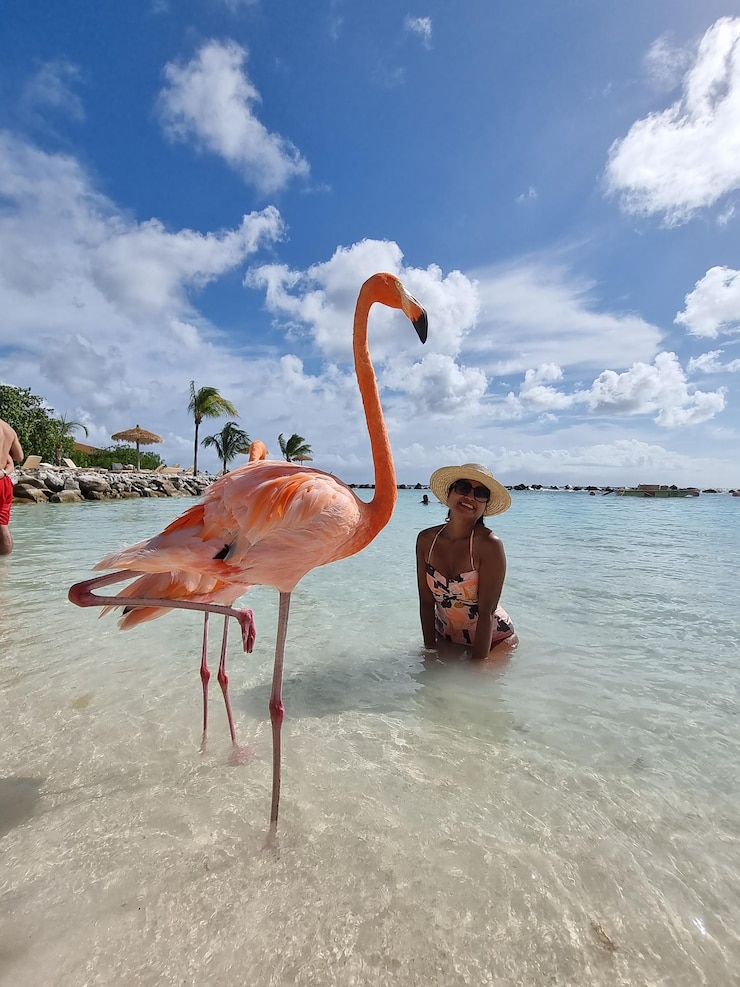 Foto glimlachende vrouw door flamingo op het strand