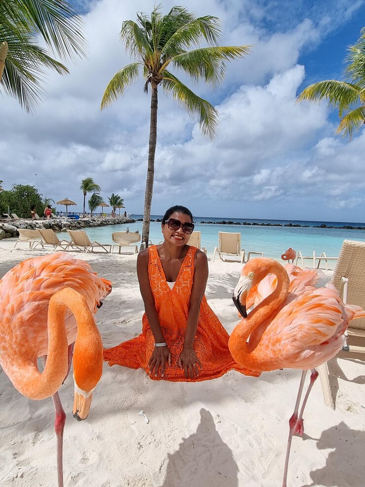 Foto glimlachende vrouw door flamingo op het strand
