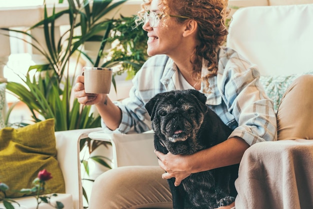 Foto glimlachende vrouw drinkt koffie terwijl ze thuis bij de hond zit
