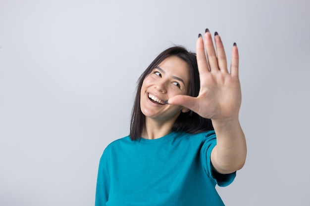 Glimlachende vrouw hief haar handpalm omhoog en naar voren alsof ze zwaaide.