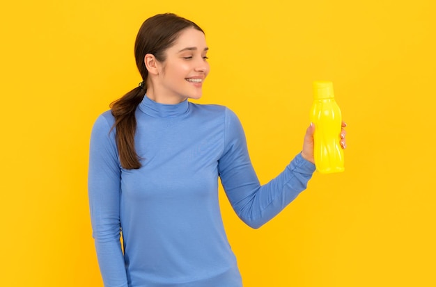 Glimlachende vrouw houdt mineraalwater dorstig jongedame met sport plastic fles gezonde levensstijl waterbalans in lichaam drinken per dag hydratatie vitaliteit worden gehydrateerd