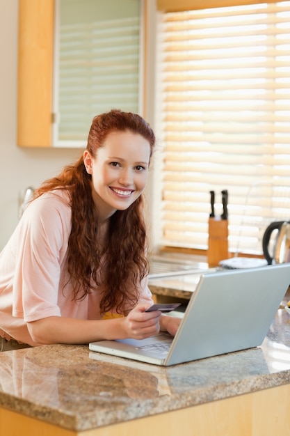 Glimlachende vrouw in de keuken die vakantie online boeken