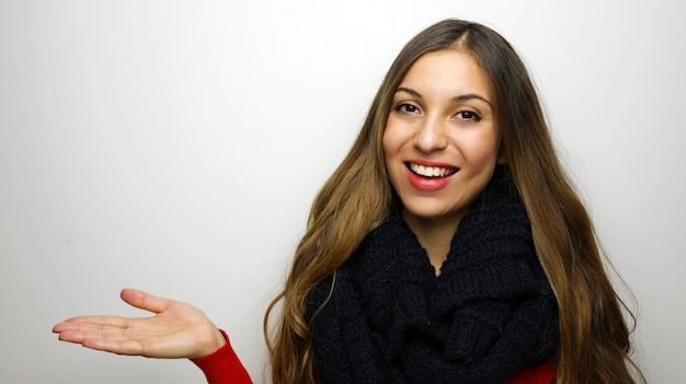 Glimlachende vrouw in de winterkleren die iets op lege palm voorstellen