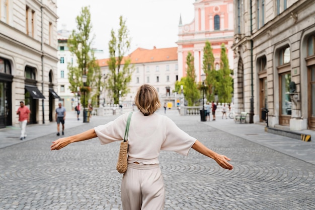 Glimlachende vrouw in een stijlvolle outfit die door de straten van de oude stad van Ljubljana loopt SloveniëReizen door Europa