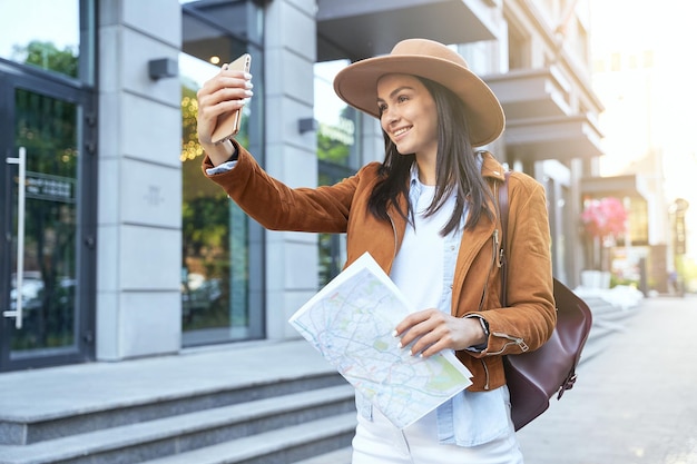 Glimlachende vrouw in hoed die foto maakt op mobiele telefoon