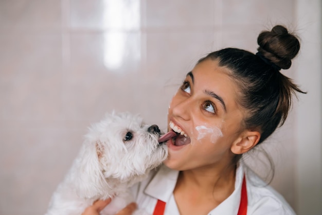 Glimlachende vrouw in keuken met schattige witte Maltese hond