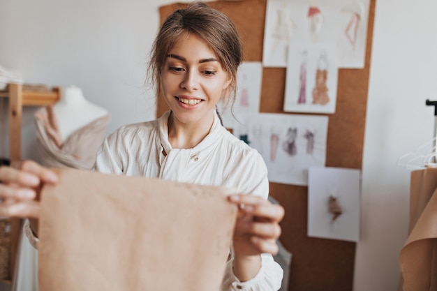 Glimlachende vrouw in lichte blouse houdt patroon vast