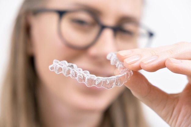 Glimlachende vrouw met behulp van doorzichtige plastic verwijderbare beugels aligner of whitening tray tandheelkundige orthodontische zorg