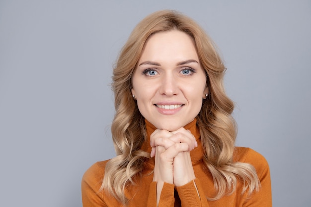 Glimlachende vrouw met blond krullend haar hand in hand met hoop in blik, kopieer ruimte, gezichtsportret.