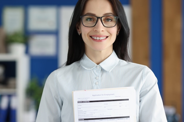 Glimlachende vrouw met een bril met sollicitatiebrief