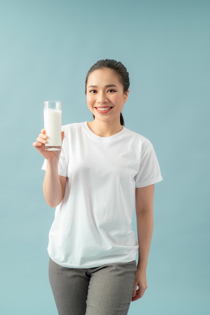 Glimlachende vrouw met een glas melk tegen een blauwe achtergrond