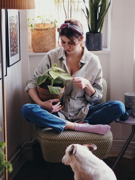 Foto glimlachende vrouw met een plant op een stoel