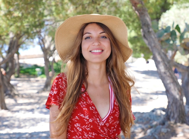 Glimlachende vrouw met hoed en rode kleding openlucht