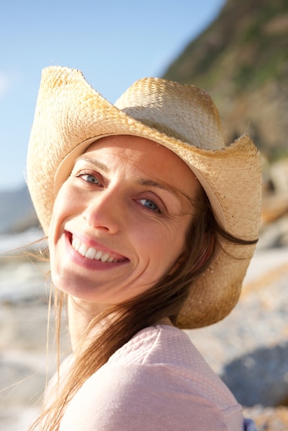 Glimlachende vrouw met hoed op het strand