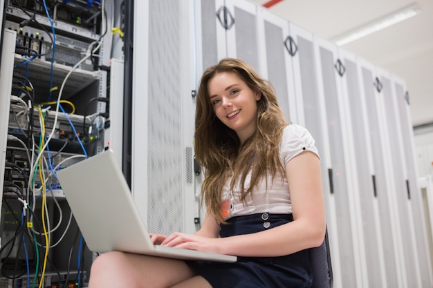 Glimlachende vrouw met laptop die met servers werkt