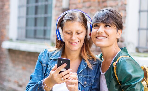 Foto glimlachende vrouw met vriend die naar muziek luistert via koptelefoon