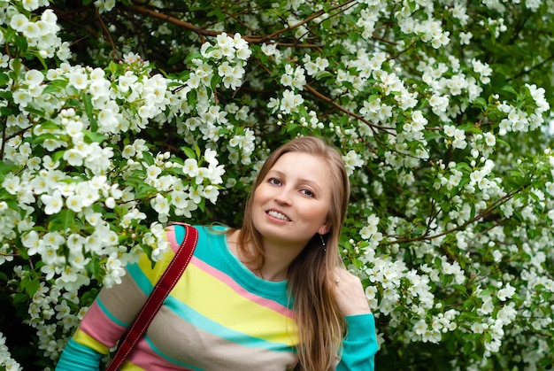 Glimlachende vrouw op de achtergrond van een bloeiende appelboom