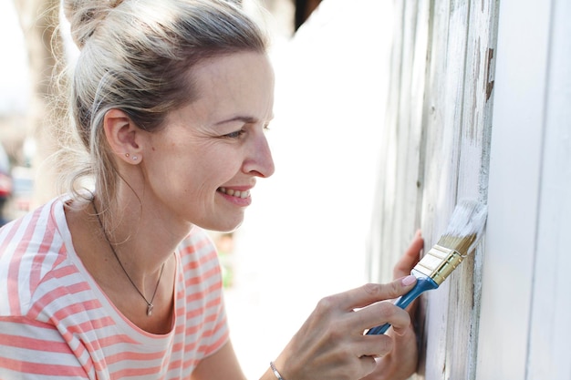 Foto glimlachende vrouw schildert een houten muur