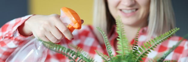 Glimlachende vrouw verwerkt een bloem in het kweekconcept van de bloempot thuis