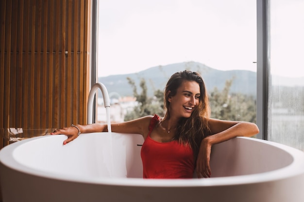 Glimlachende vrouw zit in bad in de badkamer