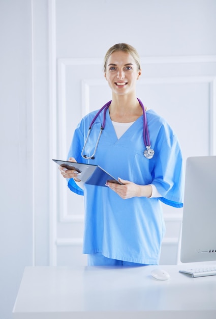 Glimlachende vrouwelijke arts met een map in uniforme status