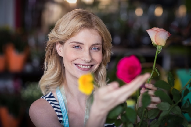 Glimlachende vrouwelijke bloemist die bloemboeket in vaas schikken bij bloemwinkel