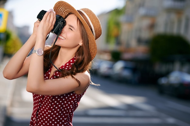 Glimlachende vrouwelijke reiziger neemt foto's op camera stadsgebouwen buiten zomer
