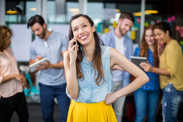 Glimlachende vrouwelijke stafmedewerker die op mobiele telefoon spreekt