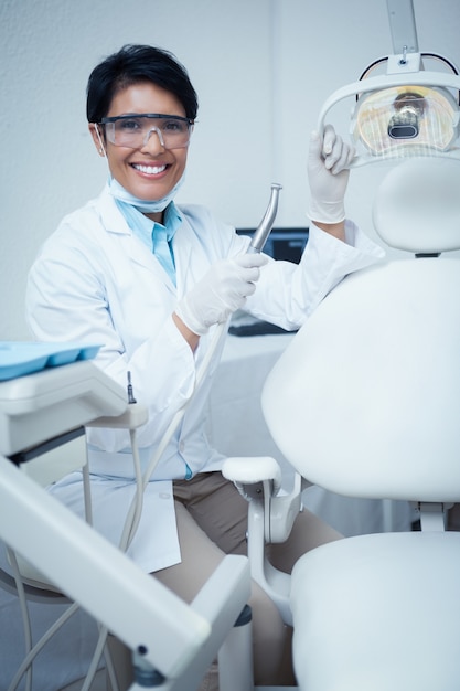 Glimlachende vrouwelijke tandarts die tandhulpmiddel houdt