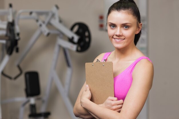 Glimlachende vrouwelijke trainer met klembord in de gymnastiek