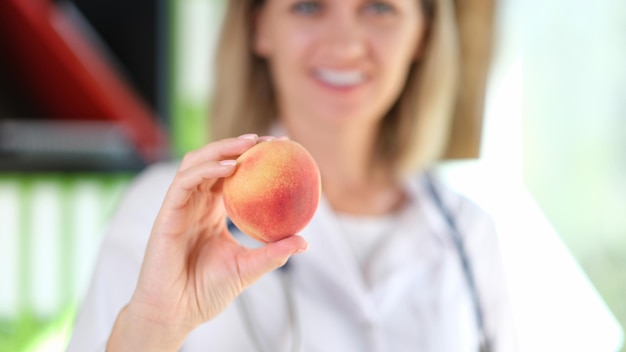 Glimlachende vrouwelijke voedingsdeskundige adviseert om fruit en vegetarisch voedsel te eten om ziektes gelukkig te voorkomen