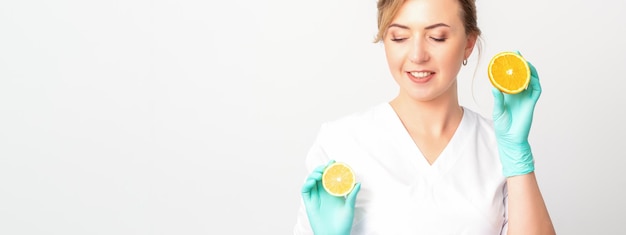 Glimlachende vrouwelijke voedingsdeskundige die een gesneden sinaasappel houdt die camera over witte achtergrond gezond dieetconcept bekijkt
