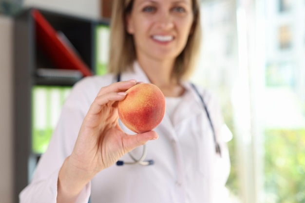 Glimlachende vrouwelijke voedingsdeskundige houdt vers perzikfruit in haar handclose-up