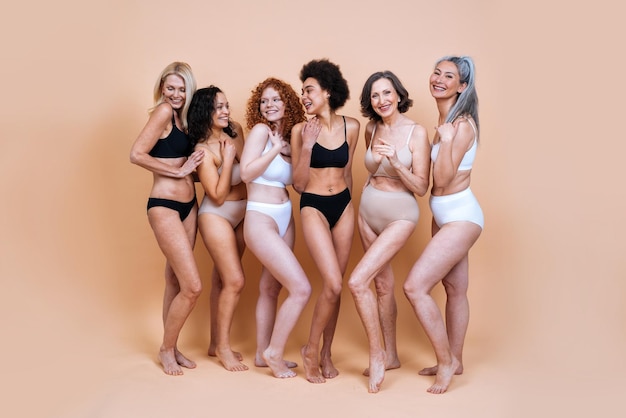 Glimlachende vrouwen die lingerie dragen tegen een gekleurde achtergrond