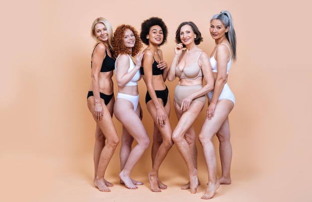Glimlachende vrouwen die lingerie dragen tegen een gekleurde achtergrond