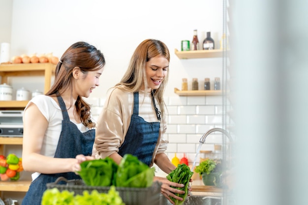 Glimlachende vrouwen die verse, gezonde saladegroenten bereiden vrouw die in de voorraadkast staat in een prachtige interieurkeuken Het schone dieetvoedsel van lokale producten en ingrediënten Verse markt