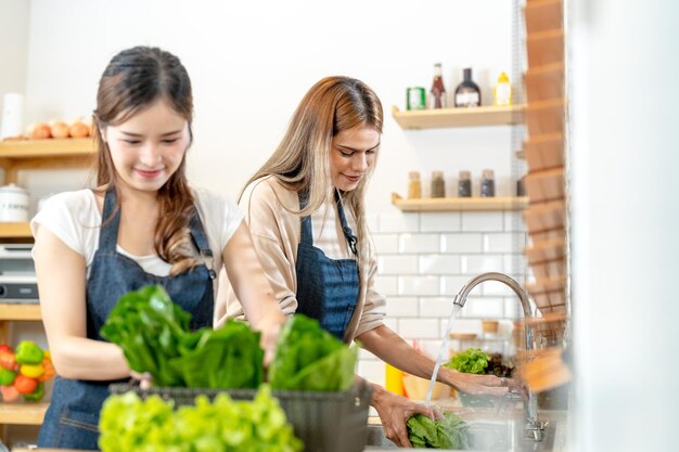 Glimlachende vrouwen die verse, gezonde saladegroenten bereiden vrouw die in de voorraadkast staat in een prachtige interieurkeuken Het schone dieetvoedsel van lokale producten en ingrediënten Verse markt