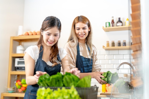 Glimlachende vrouwen die verse, gezonde saladegroenten bereiden vrouw die in de voorraadkast staat in een prachtige interieurkeuken Het schone dieetvoedsel van lokale producten en ingrediënten Verse markt