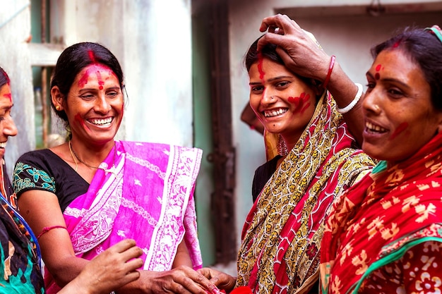 Foto glimlachende vrouwen in sari's vieren holi in de open lucht.